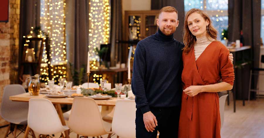 a couple posing with festive lights in the background